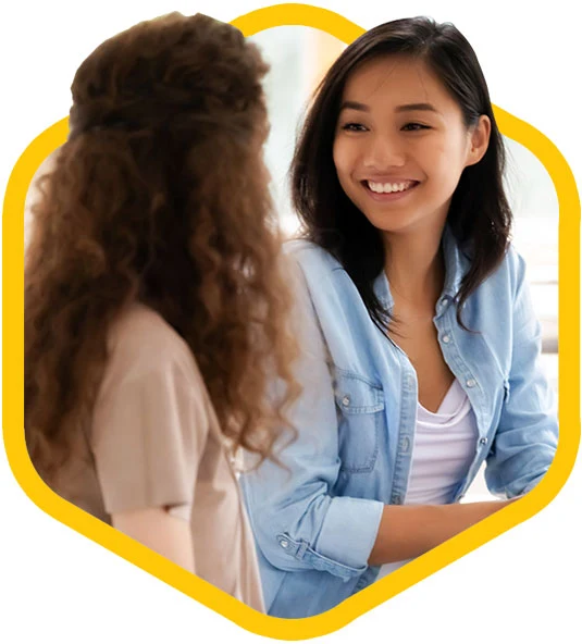 Two female coworkers discussing the definition of employee engagement.